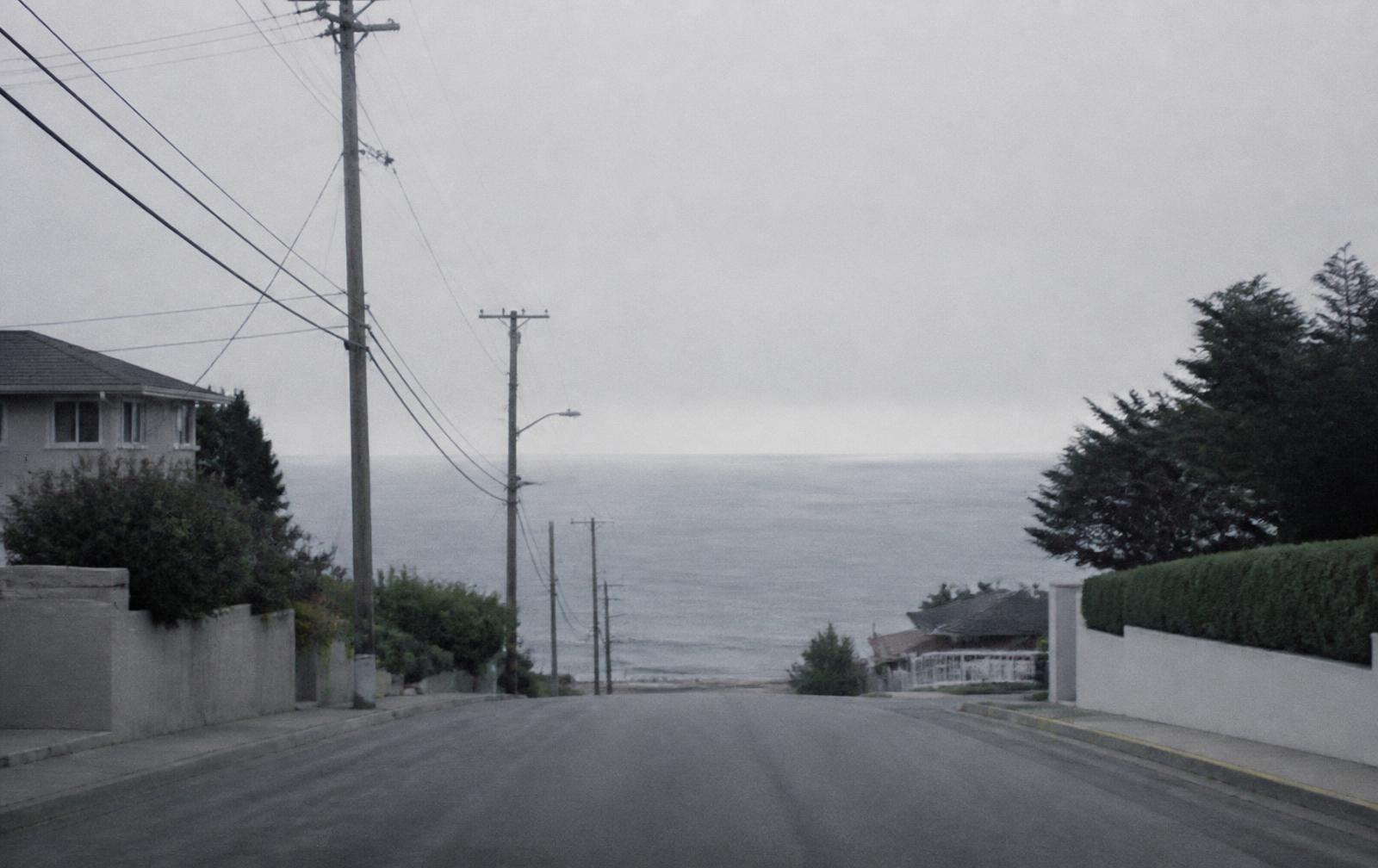 A flat gray Pacific horizon at the end of a residential street under marine layer fog